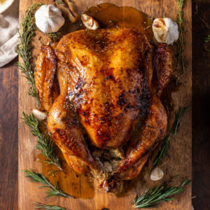A stunning, photorealistic overhead shot of the finished dry-brined turkey, beautifully roasted to a deep, golden-brown perfection.