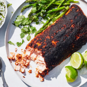 A close-up, mouth-watering shot of the finished spicy blackened salmon dish, plated with fresh sides.