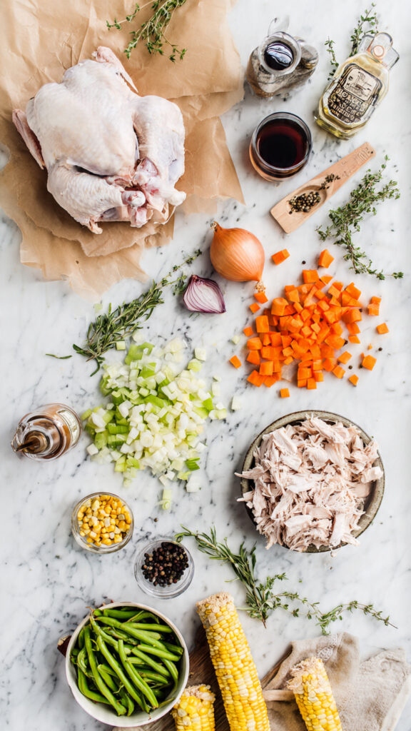Raw ingredients for Leftover Turkey Soup including turkey carcass, vegetables, and fresh herbs.